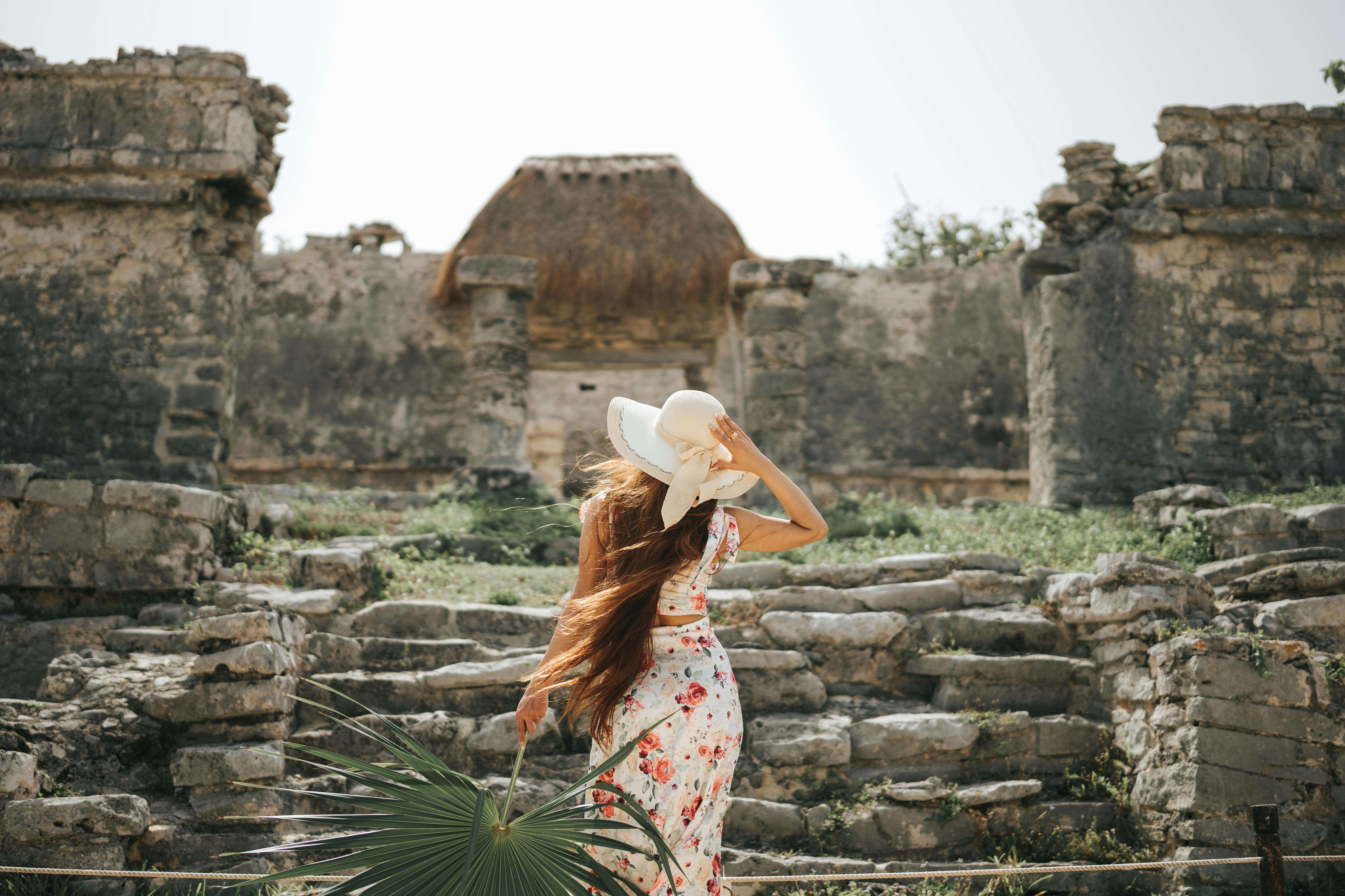 A woman in a floral dress explores the ancient Tulum ruins in Mexico during summer.