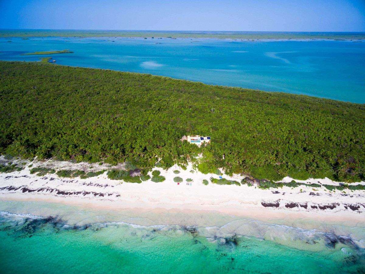 Overhead view of Hacienda Chekul’s private beach with powdery white sand, turquoise waters, and dens